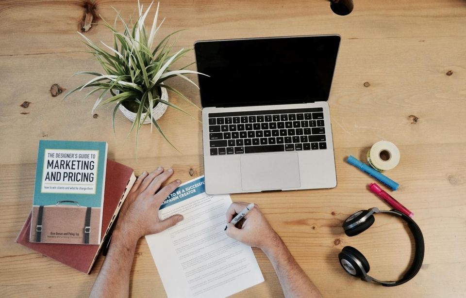 Desk with a laptop, a notebook and a book on marketing and pricing